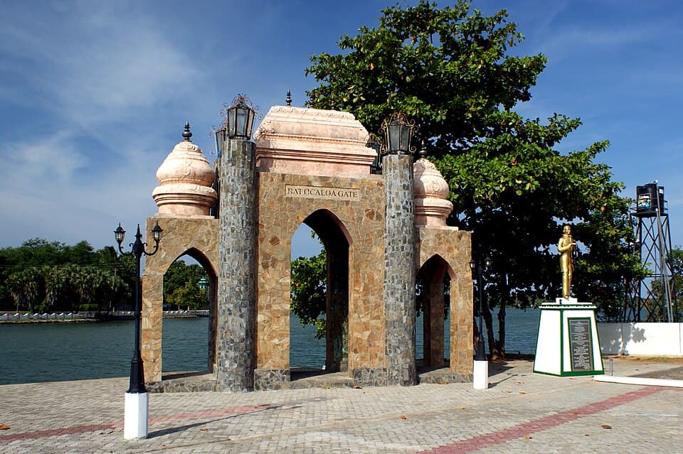 The Batticaloa Gate memorial arch on the lagoon shore, with the statue of William Ault beside it