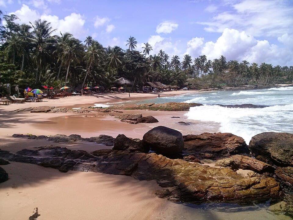 Goyambokka Beach near Tangalle, with granite boulders in the shallows and parasols on the sand
