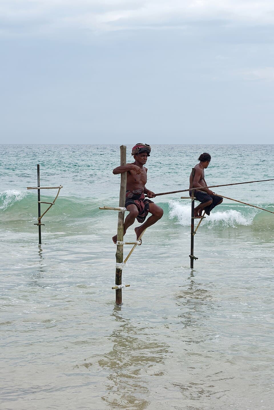Stilt fishermen on their poles in the surf at Koggala