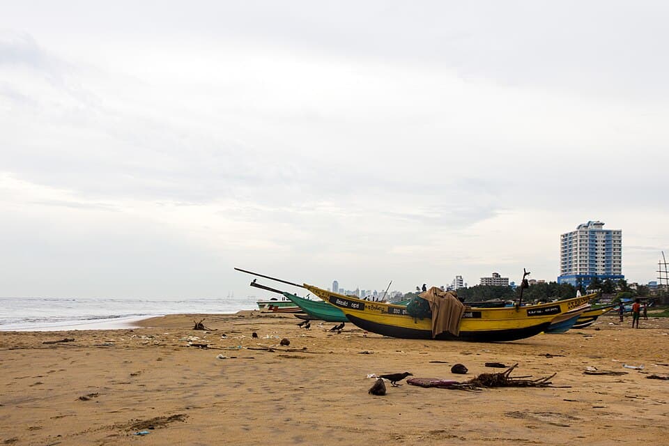 Fishing boats on Mount Lavinia Beach with the suburb's tower blocks behind