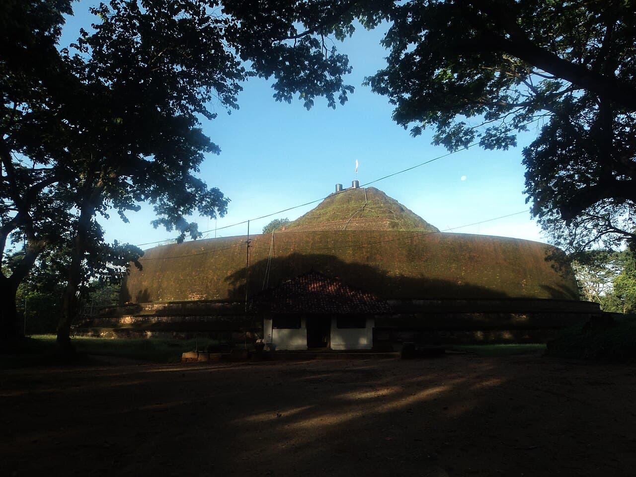 The grass-covered Yudaganawa stupa mound with the small image house at its base