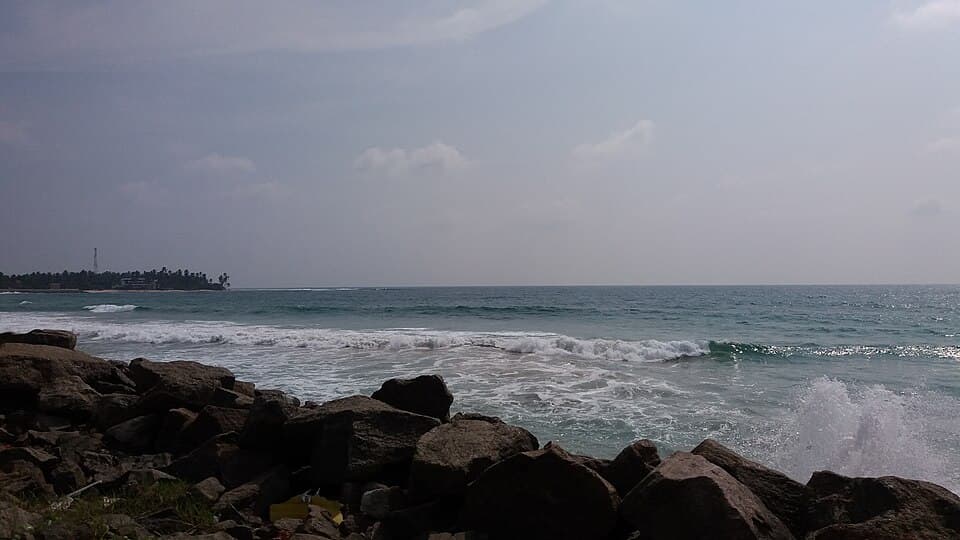 Waves on the rocks at Kirinda Beach, with the village shore beyond