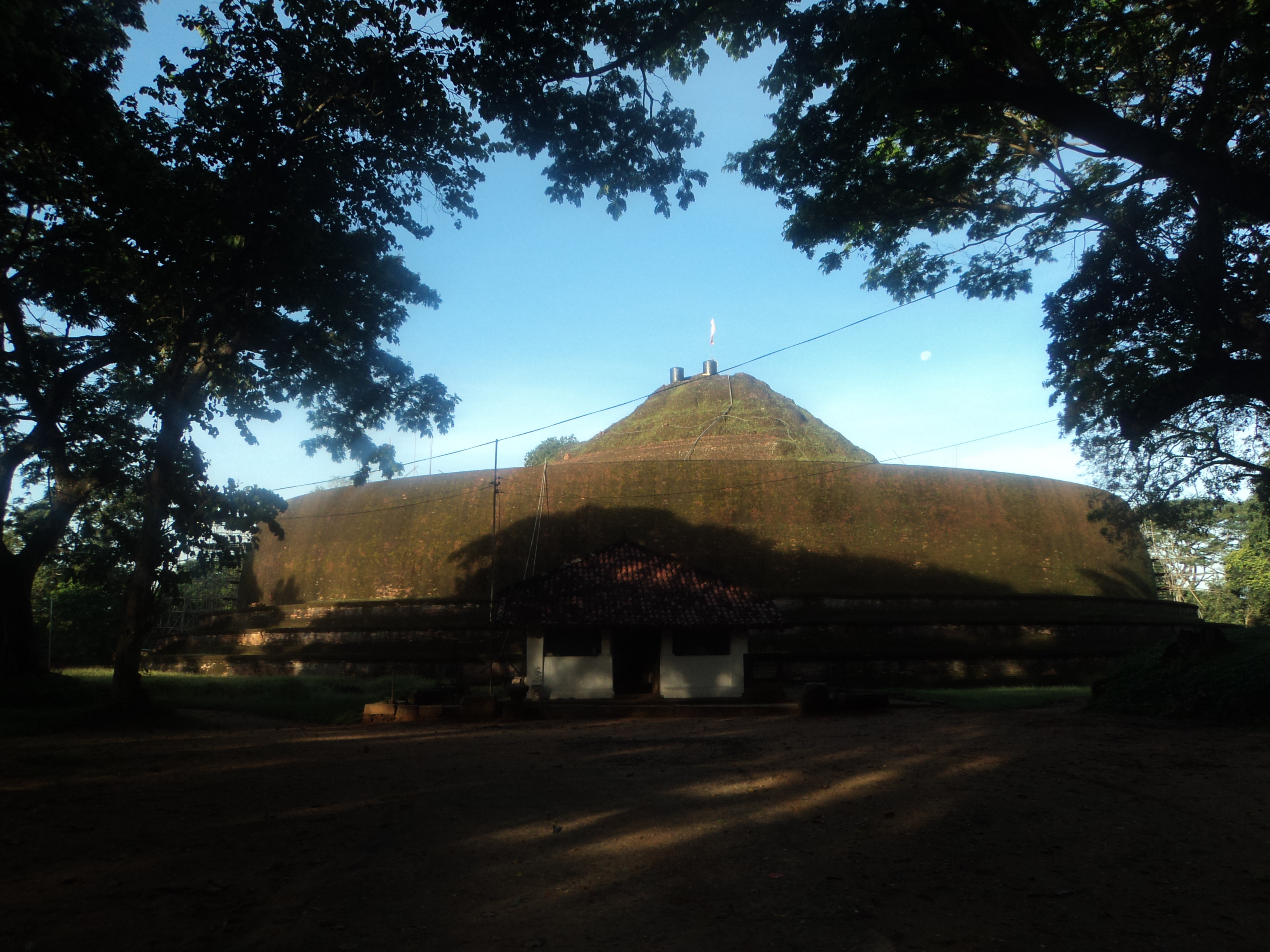 The grass-covered Yudaganawa stupa mound with the small image house at its base